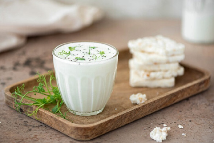 A glass of buttermilk in a wooden tray